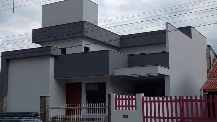 Casa com fachada pintada em tons de cinza, detalhes brancos e volumes geométricos.