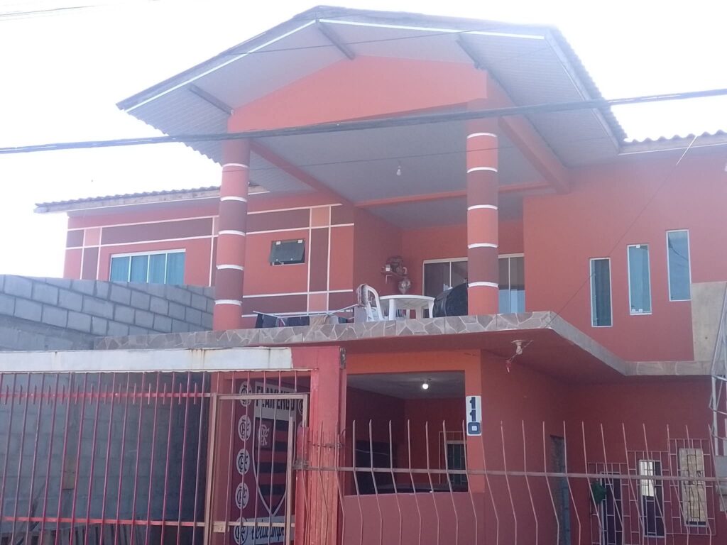 Residência com pintura externa coral, colunas e frisos brancos.
